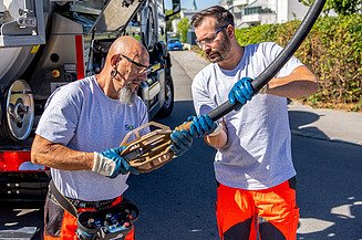 Kanalservicearbeiten an einem Spezialfahrzeug, während ein Werkzeug für Reinigungs- oder Wartungsarbeiten vorbereitet wird.